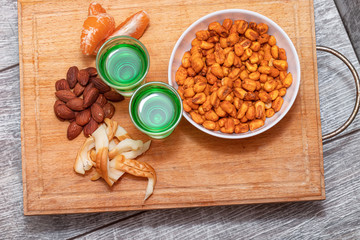 Two shot of absinthe stand on a wooden board.