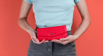 Minimal fashion concept. Woman holding a trendy red purse on pink background. Crop photo, studio shot