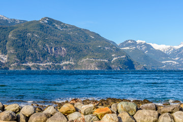 Fantastic view over ocean, snow mountain and rocks at Furry Creek Dive Site in Vancouver, Canada.