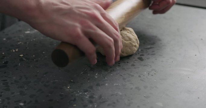 Slow motion man rolling dough on concretre countertop