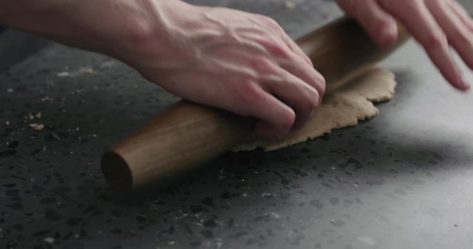Slow motion man rolling dough on concretre countertop