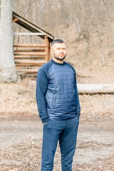 Attractive man with beard is standing in a park at sunset. Stylish Hipster man. Autumn Fashion Look