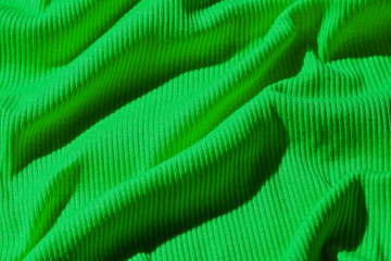 Fototapeta na wymiar Background of crumpled green neon fabric texture closeup.
