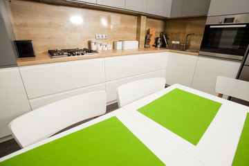 Empty white dining table with green details at kitchen.