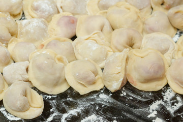 Dumplings, cooked at home, lie on a plate, sprinkled with flour.