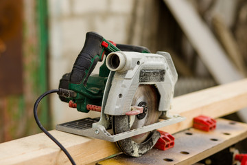 A modern green circular saw lies on a wooden table in the workshop. Closeup of a circular saw