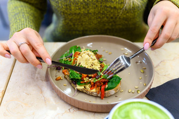 toast with homemade hummus and baked vegetables, matcha latte green tea cup, and woman ready eats