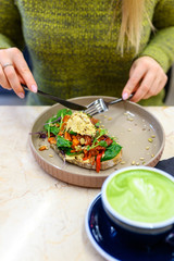 toast with homemade hummus and baked vegetables, matcha latte green tea cup, and woman ready eats. vertical photo