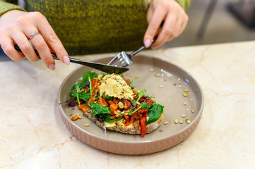 toast with homemade hummus and baked vegetables and woman ready eats