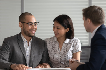 Happy multiethnic couple visiting banker or broker in office
