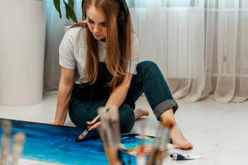 Art, the work of the artist. Young beautiful girl artist paints a picture. Workshop of the artist. The process of creativity. Drawing and paint. Inventory of the artist. Close-up.