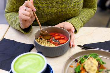 raw healthy food breakfast and woman, ready to eats. smoothie bowl, toast with hummus, and matcha latte green tea cup on the table