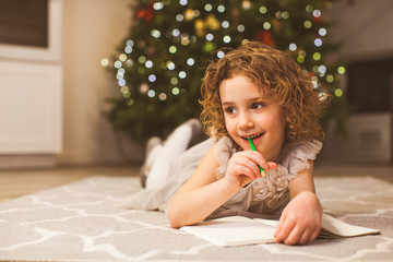 Smiling girl thinking about Christmas wish list