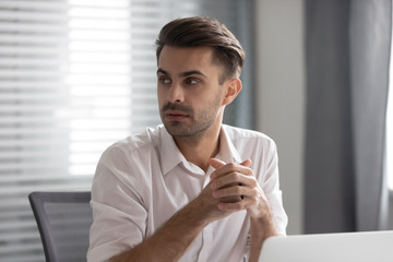 Pensive male employee look to side listen to coworker talk