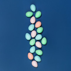 Several pastel color dyed easter eggs on blue in flat lay with copy space. Subtle colors Happy Easter minimal concept card or banner