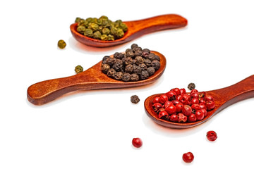 Three types of pepper peas in wooden spoons on a white background.