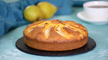 Homemade pear pie on a blue table with pears in the background.