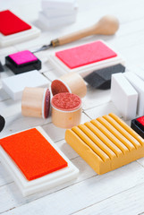 handicraft equipments, ink pads, lino cutter, paint roller and plasticine blocks on white wood table