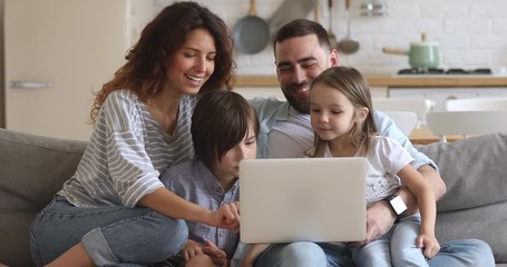 Smiling family of four using laptop, shopping at home. - Powered by Adobe