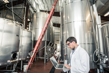 Technician monitoring and documenting readings of gauges on a steel tank. Red Lodge, Montana, USA