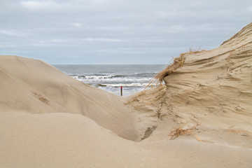 View on beach with a beach pole and the North sea between two dunes 