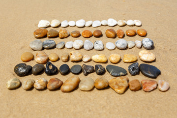 Horizontal in Reihen angeordnete, bunte Steine am Strand, Land Art