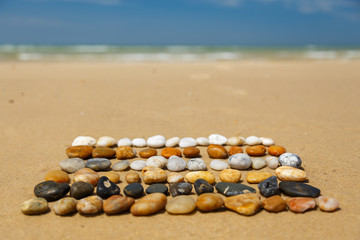 In Reihen angeordnete, bunte Steine am Meer, Land Art