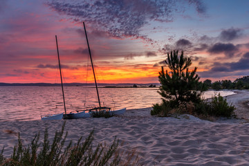 Zwei Katamarane liegen während des Sonnenuntergangs am Stand des Lac d'Hourtin, Frankreich,