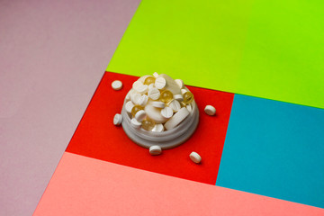 Cap with pills in and around it on a colorful background