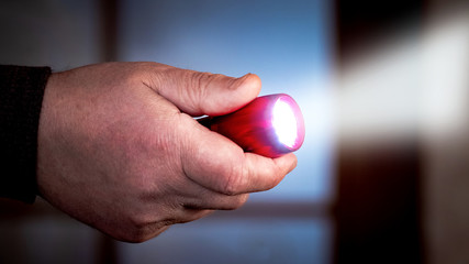 A man holds in his hand a flashlight in a dark room. Penetration into another's home_