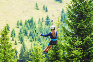 A young girl takes a picture of herself on a cellphone while descending on a zipline_