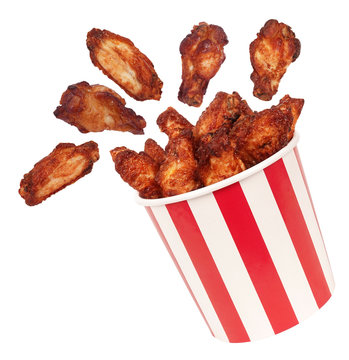 Perfect chicken wings flying around from big red white stripes bucket box