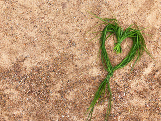 Heart on the beach. Wicker heart made of natural materials on the sandy beach. Concept with a symbol of love with copy space.