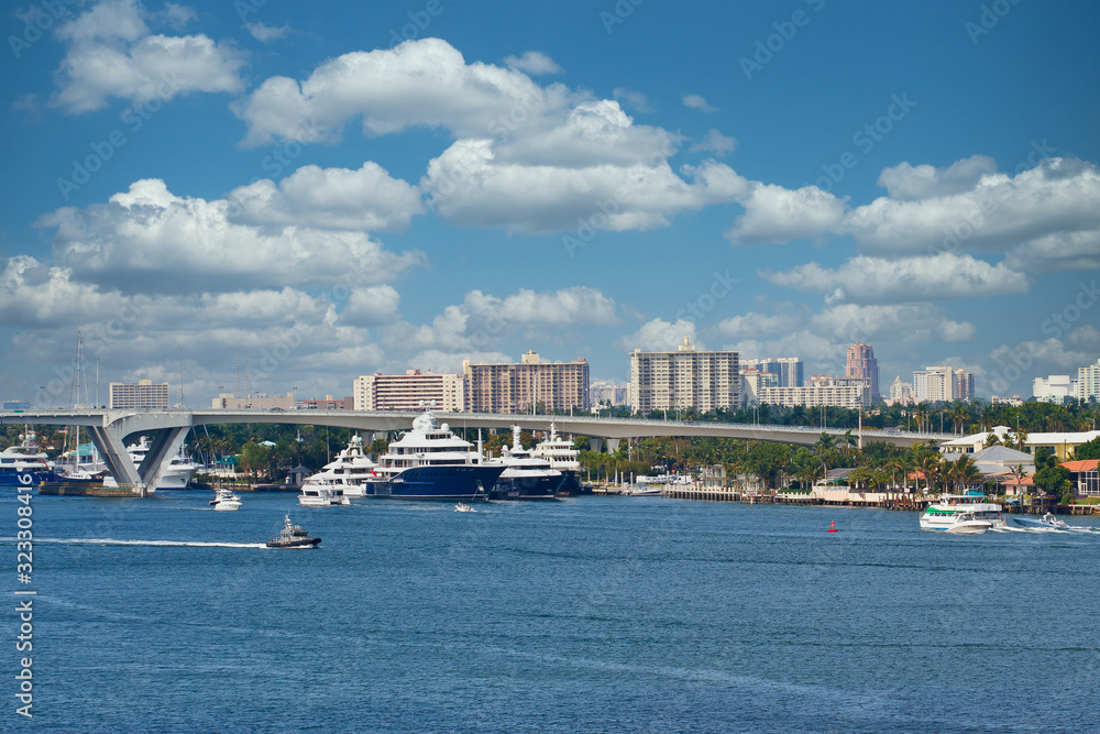 Poster Many blue and white luxury yachts by a drawbridge in a shipping channel