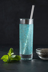 Tropical blue cocktail with chia seeds in glass on black background. Close up. Vertical. Detox and freshness.