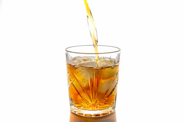 Pouring whiskey in a glass with ice. front view. Isolated