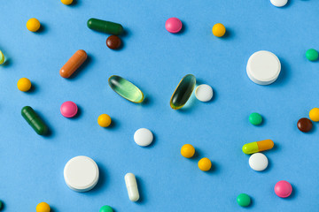Background of pills, tablets, vitamins, drugs, omega 3 fish oil, gel capsules, medicament and food supplement for health care on blue