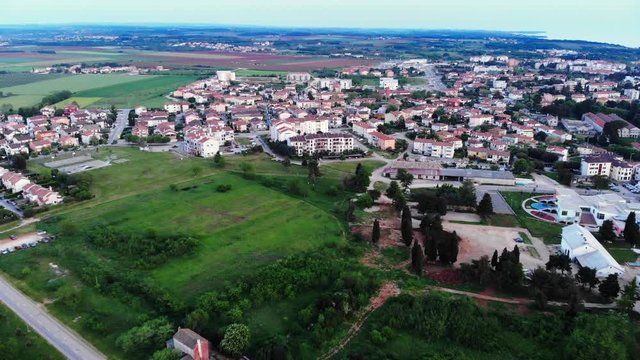 AERIAL: Flying down into the town of Umag, Croatia. Cute white houses surrounded by nature.