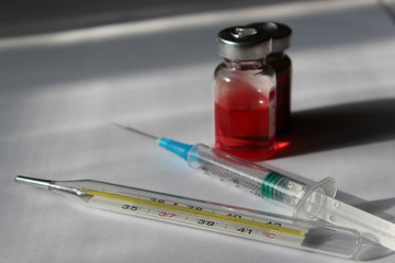 Vaccine with a syringe and a thermometer on a white background