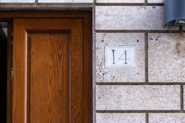 number 14, ancient house number plate on brick wall, Italy