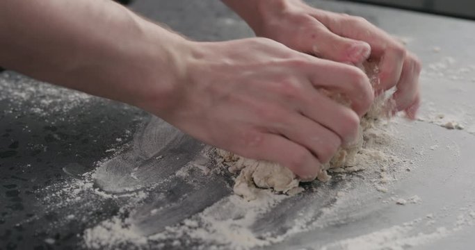 Slow motion man working with dough on concrete countertop