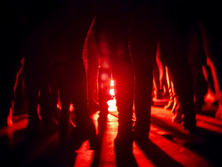 Silhouettes of feet in a nightclub against a bright red lantern in the center with shadows...