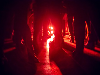 Silhouettes of feet in a nightclub against a bright red lantern in the center with shadows...