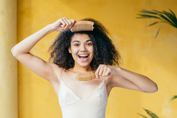 Close-up portrait of her she nice attractive glamorous perfect well-groomed cheerful cheery girlish wavy-haired girl closing covering eye with wooden comb isolated over beige background