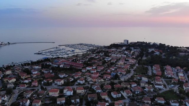 Summer sunset over Umag, Croatia. Aerial cityscape revealing ACI Marina. Panning left shot