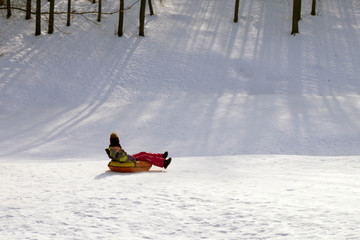 Fototapeta na wymiar girl riding a tubing from a snow slide
