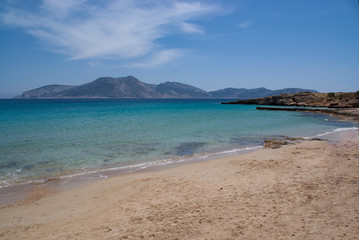 Fototapeta na wymiar A tranquil, quiet beach on the beautiful Greek island of Koufonissi set in the Cyclades. A view from the pale sand of the shore to the island of Keros on the horizon. 