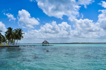 a house in the middle of the turquoise water in a paradise background