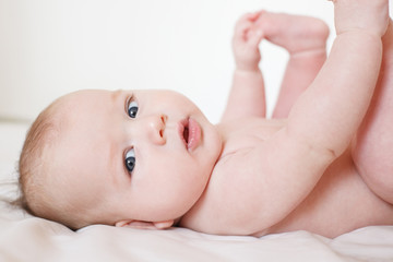 cute baby lies on his back and holds his legs with his hands. On a white background. Selective focus.