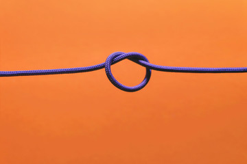 knot of braided wire of lilac color on an orange background